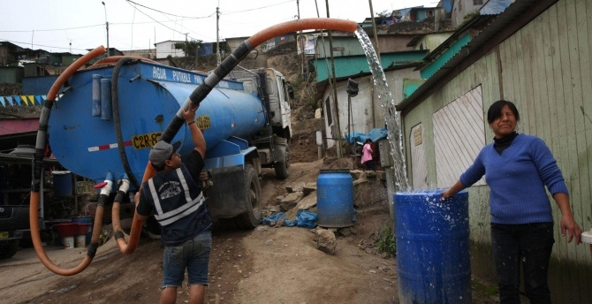 Marisol Sulca next to her family’s water bin being filled by the local water truck operator, in Pamplona Alta, Peru, Sunday, Oct. 21, 2018. (AtlasNetwork.org Photo/Rodrigo Abd)