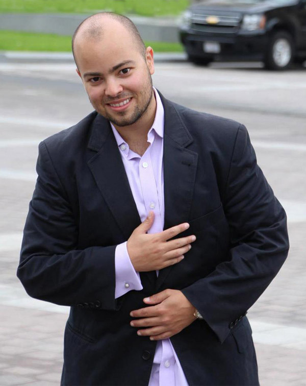 A photo of Carlos Goes standing outside wearing a blazer.