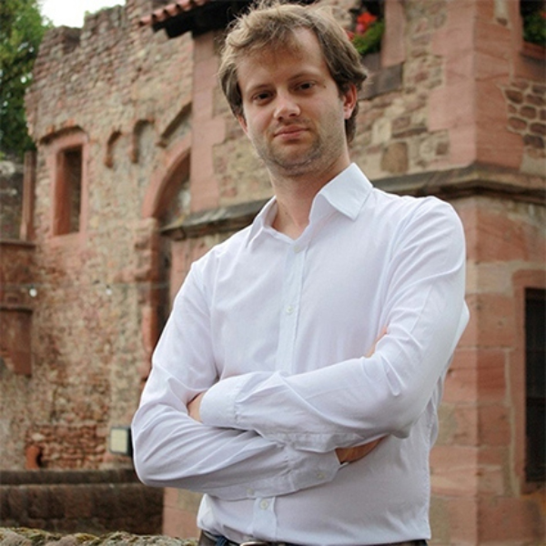 A photo of Axel Kaiser in front of a stone building.