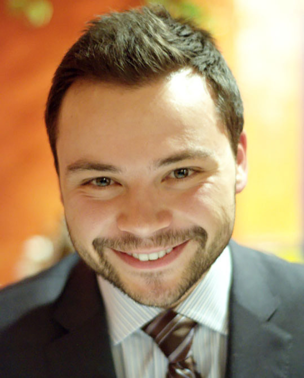 A photo of Diogo costa smiling in full suit and tie.