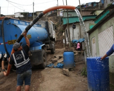 Marisol Sulca next to her family’s water bin being filled by the local water truck operator, in Pamplona Alta, Peru, Sunday, Oct. 21, 2018. (AtlasNetwork.org Photo/Rodrigo Abd)